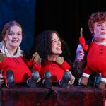 2 young females and 1 young male performing with red puppets in a scene from Grimm Tales.