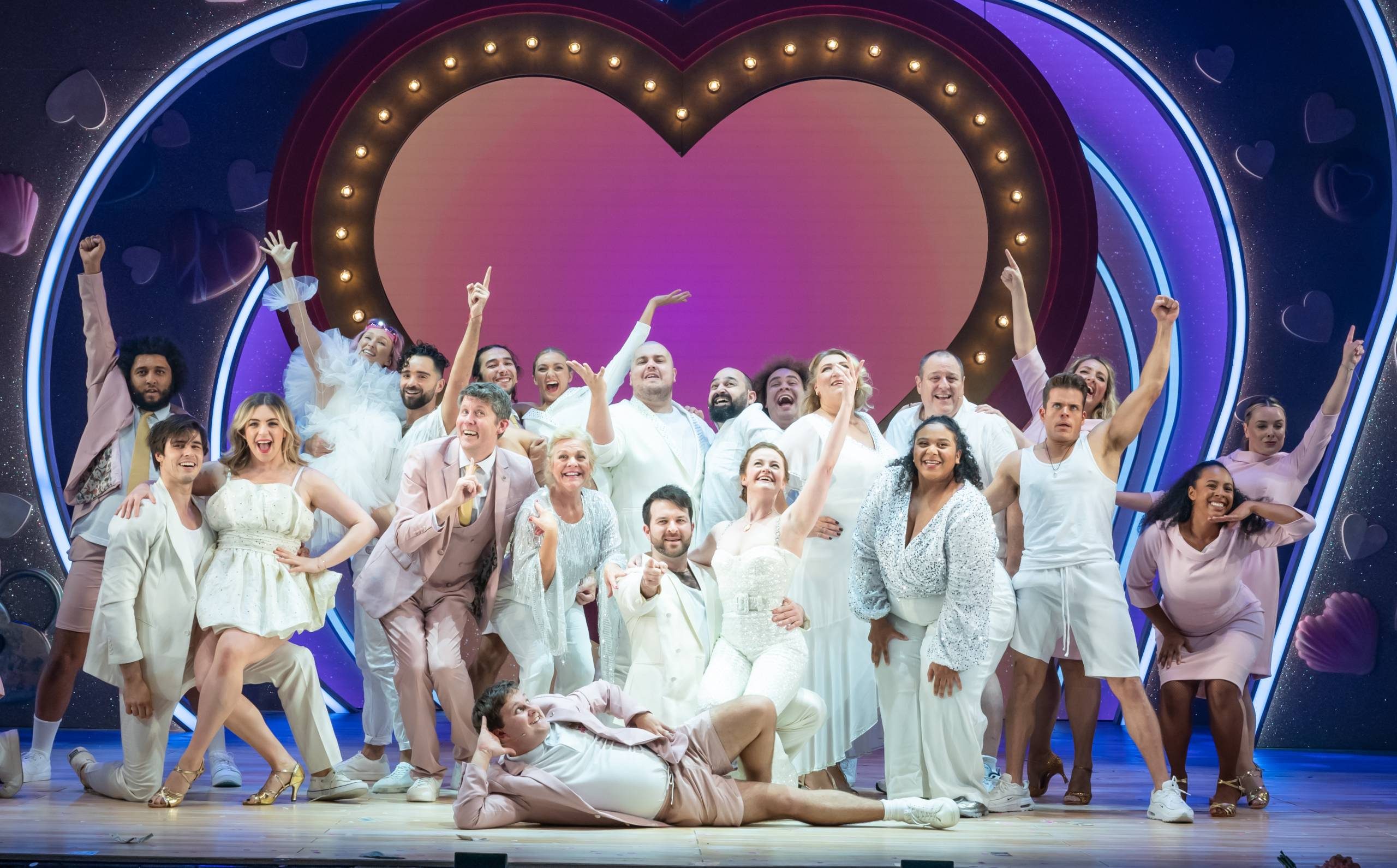the entire cast of I Should Be So lucky dressed in white and posing.