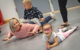 A woman and young girl are smiling whilst laying on the floor and participating in one of the activities at our Family Fun Day.