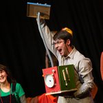 A man holding a box with a clock on it and his arm raised whilst performing at our Family Fun Day at MAST Mayflower Studios.