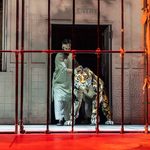 A large puppet tiger galres through cage bars
