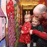 Man and 2 children admiring hand-drawn artwork on wall during Countdown to Christmas at Mayflower Studios.
