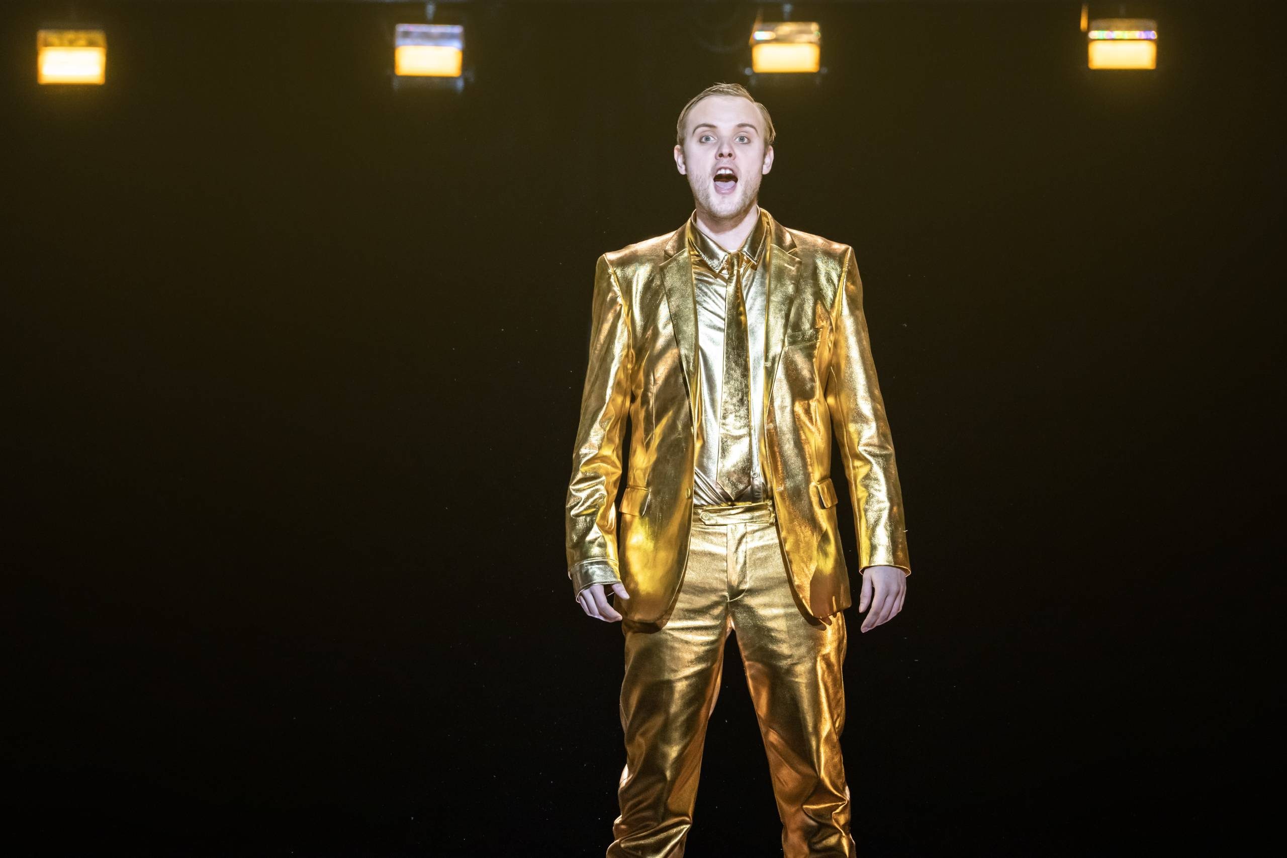 Alexander Chance singing in gold suit