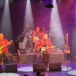 Dozy Beaky Mich & Tich in red jackets performing on stage, 3 guitarists 1 drummer