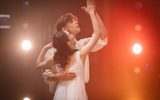 Romeo (Harris Beattie) and Juliet (Saeka Shirai) waltz in white, looking up at their hands raised, touching palm to palm.