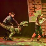 Velociraptor puppet follows ranger as she gestures off camera