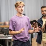 Tom Sturgess in purple t-shirt gesturing in front of himself