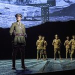 Lieutenant Nicholls (Chris William) standing at ease with soldiers behind him.