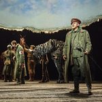 Klausen (Jack Lord) staring out as Friedrich (Alexander Ballinger) walks passed horse Joey (puppeteers Matthew Lawrence, Rafe Young, Felicity Donnelly) and Tophorn (puppeteers Rianna Ash, Chris Milford, Thomas Goodridge)