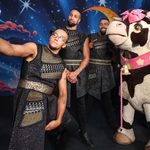 Family Trot (Perri Kiely, Ashley Banjo and Jordan Banjo) take a selfie on a mobile with the pantomime cow