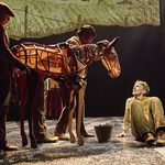 Foal Joey (puppeteers Diany Samba-Bandza, Jordan Paris, Eloise Beaumont-Wood) looking down at Albert Narracott (Tom Sturgess)