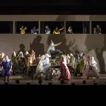 Rigoletto (Daniel Luis de Vicente) striding along a table in the midst of a debaucherous party