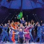 Cast of Mary Poppins reaching upwards, Mary elevated behind them, her parrot umbrella projected large above in the starry night sky.