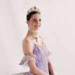 Sugar Plum Fairy (Emma Hawes) smiling, hands folded in front of lilac bodice and white tutu, wearing diamond choker and tiara