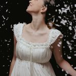 Clarra (Ivana Bueno) looking up as snow falls, wearing white sleeveless dress