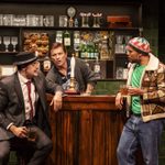 Two men (Peter Watts, Bradley John) drinking at a bar, the barman (Darryl Paul) watching them talk.