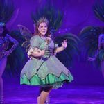 The Spirit of the Beans (Jacqueline Hughes) dancing in green dress, crown, wings and sceptre with carnival backing dancers in shadow behind