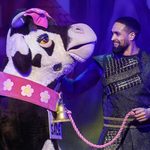 A smiling Jack (Ashley Banjo) pats the pantomime cow wearing a pink bow, collar, bell and for sale sign