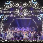 Cast taking bows wearing silver and blue on white and blue stage