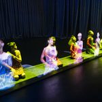 Holograms mirror the moves of people knelt behind them.