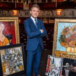 George Rainsford in theatre surrounded by paintings