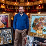 Peter Ash in theatre surrounded by paintings