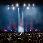 Back of audience with lights shining down on a woman on stage