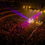 Aerial view of theatre, audience looking at purple and yellow lit stage