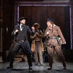 Wild Bill Hickok (Vinny Coyle) and Calamity Jane (Carrie Hope Fletcher) face off, Bill's fists raised, Calamity's on the way, a clarinet player in the background of the saloon