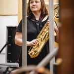 Claire Greenway (Doc) photographed through bars holding a saxophone