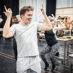 Dan Partridge points his fingers in the air as the cast dance behind him