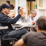 Nick Winston (Co-Director) pointing with a pencil from a table of people busy with scripts and ipads