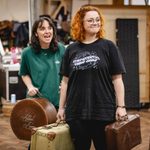 Seren Sandham-Davies (Katie Brown) looking excited and Carrie Hope Fletcher (Calamity Jane) looking smugly triumphant holding old luggage cases