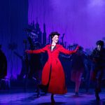 Mary Poppins (Stefanie Jones) in red long coat and soot smudged cheek dances with chimney sweeps