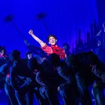 Bert (Jack Chambers ) in red shirt, raised his fist in the air at night, surrounded by chimney sweeps