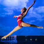 Liam Mower wearing old style red and white swim suit leaps against cloudy blue sky