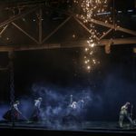 Sparks fly down from metalworks as workers sweep in the darkness below