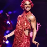 Lola (Johannes Radebe) in sparkly red small dress and short red wig