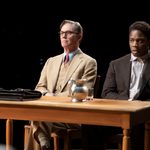 Atticus and Tom sitting at Courtroom table with leather satchel, jug and glass of water on