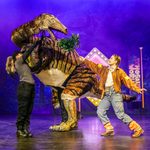 White brunette ranger offers large segnosaurus puppet some leaves