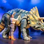 Female ranger pats side of large triceratops puppet