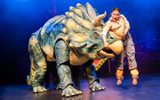 Large triceratops puppet lifts shocked white brunette ranger up by its horn