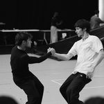 041125_SadlersWells_Quadrophenia_REHEARSAL-1-0132 Black and white image of men clasping hands, counter-balancing as they stare wildly at each other