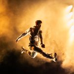 Man in suit jumping in air with gold background.