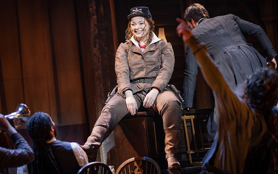 Carrie Hope Fletcher sits on a bar piano